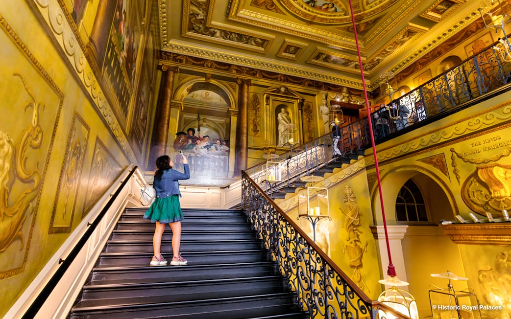 Tourists exploring ornate staircase at Kensington Palace, London.