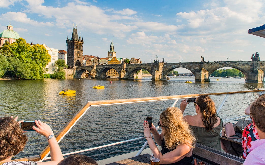 Prague Charles Bridge view from boat tour with tourists taking photos.