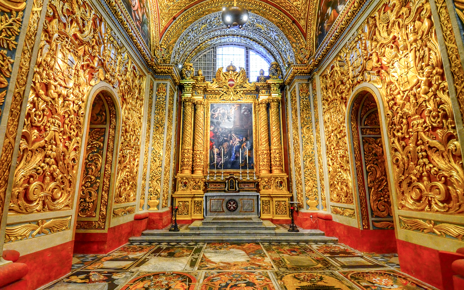 Valletta ornate cathedral interior with gilded walls and detailed frescoes.