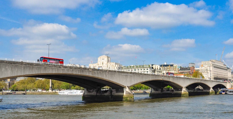 Waterloo Bridge over the River Thames with a red double-decker bus in London.