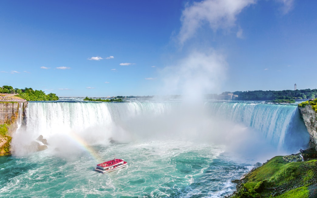 Maid of the Mist boat near the base of Niagara Falls with a rainbow in the mist.