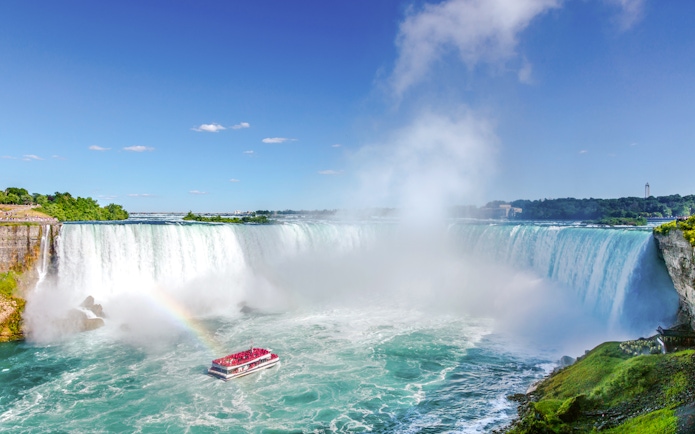 Maid of the Mist boat near the base of Niagara Falls with a rainbow in the mist.
