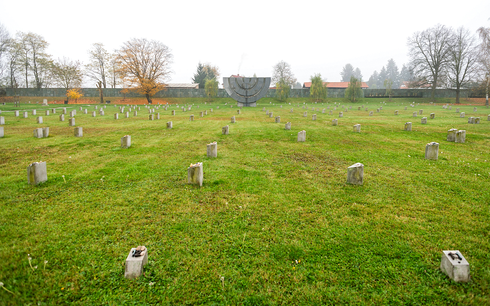 Terezin Concentration Camp memorial field with stone markers and a large menorah sculpture.