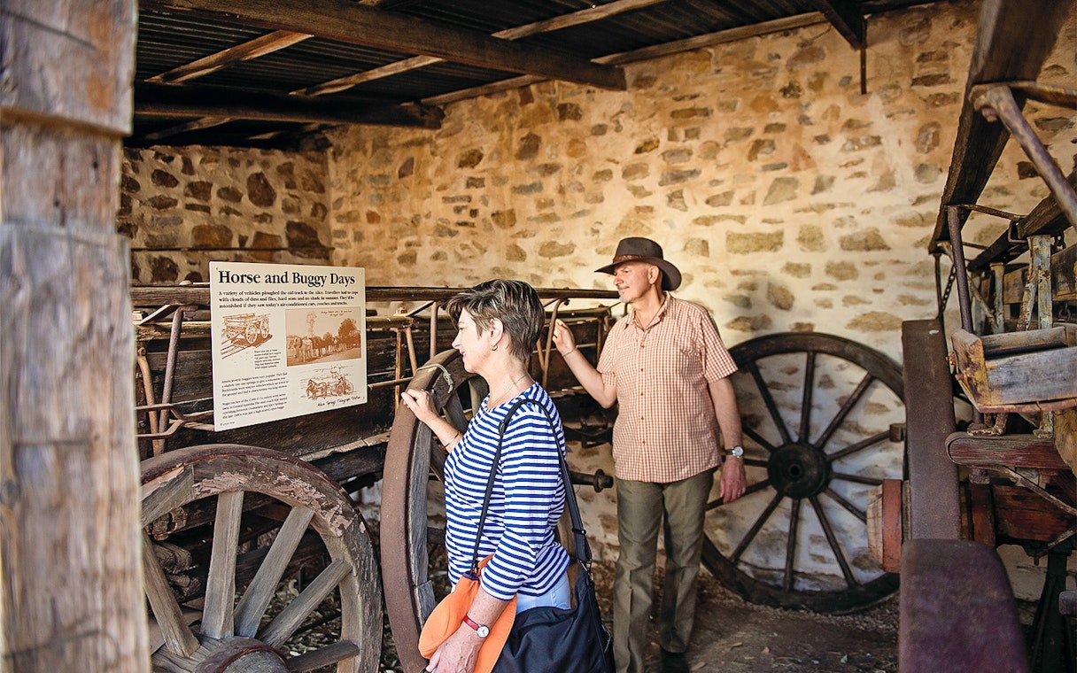 Visitors exploring historical wagon display in Alice Springs.