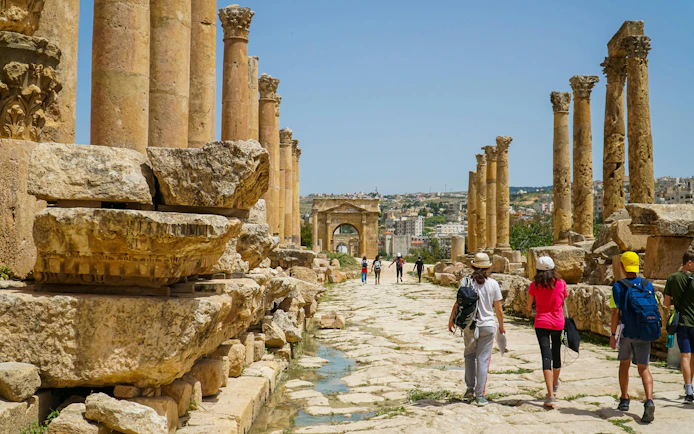Tourists walking through ancient Roman ruins in Jerash, Jordan.