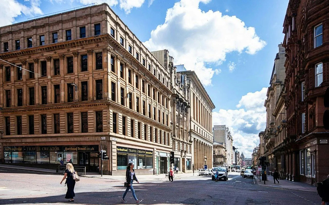 Historic street view in Glasgow with pedestrians and classic architecture.