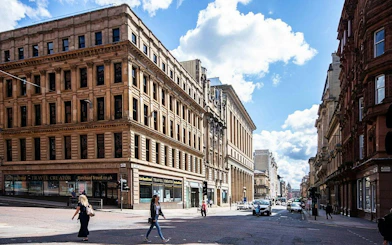 Historic street view in Glasgow with pedestrians and classic architecture.