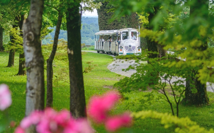 Tourist train in Parco Giardino Sigurtà, Italy, surrounded by lush greenery.