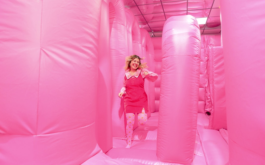 Person enjoying the pink bouncy house at the WONDR Experience in Amsterdam.