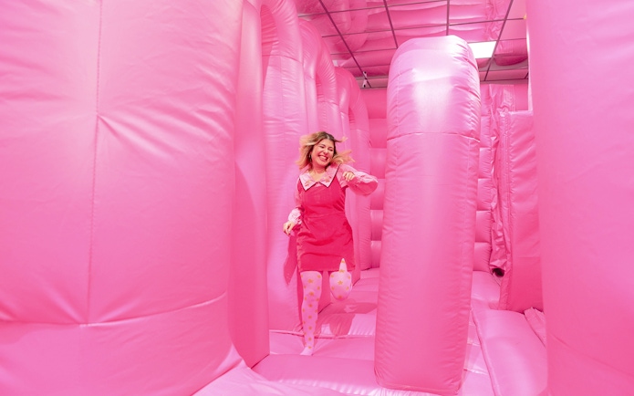 Person enjoying the pink bouncy house at the WONDR Experience in Amsterdam.