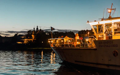 Nighttime river cruise in Krakow with illuminated boat and city skyline.