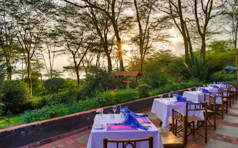 Outdoor dining setup at bush camp with sunset view, part of 2-Day Masai Mara Safari, Nairobi.