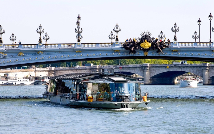 Bateaux Parisiens cruise on the Seine River under Pont Alexandre III in Paris.