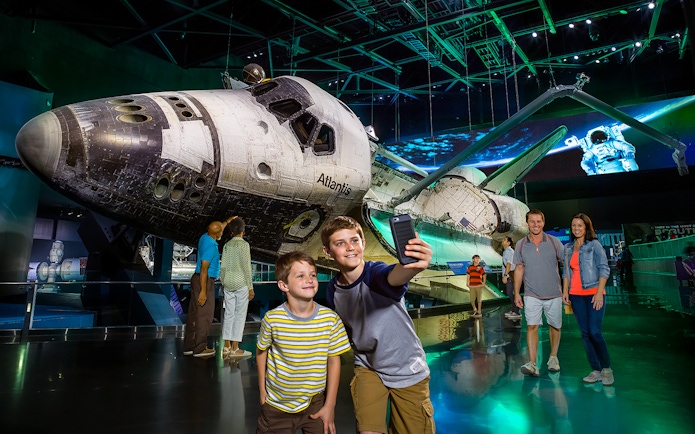 Space Shuttle Atlantis exhibit at Kennedy Space Center with visitors taking photos.