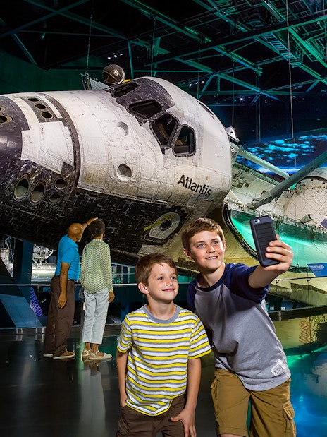 Space Shuttle Atlantis exhibit at Kennedy Space Center with visitors taking photos.