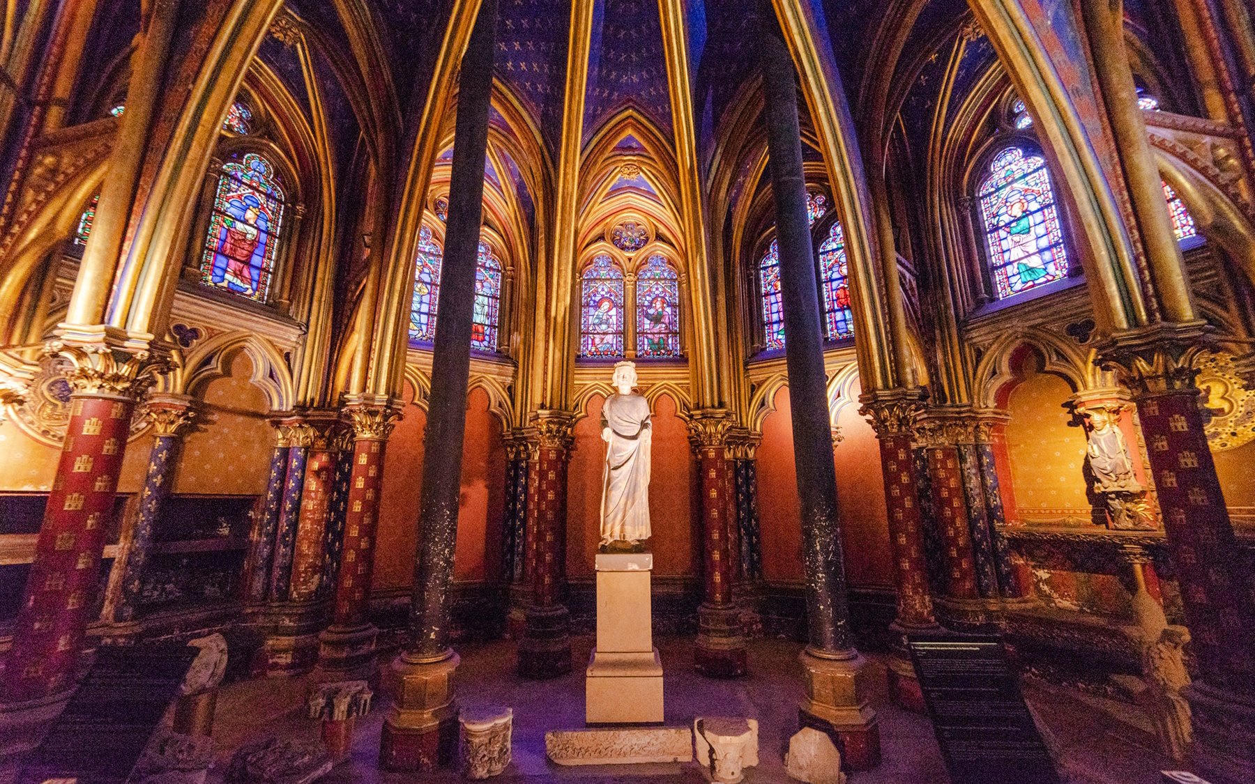 Sainte-Chapelle interior with stained glass windows and central statue in Paris, France.