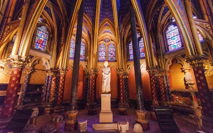 Sainte-Chapelle interior with stained glass windows and central statue in Paris, France.