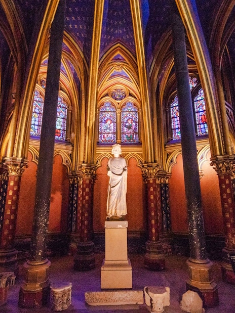 Sainte-Chapelle interior with stained glass windows and central statue in Paris, France.