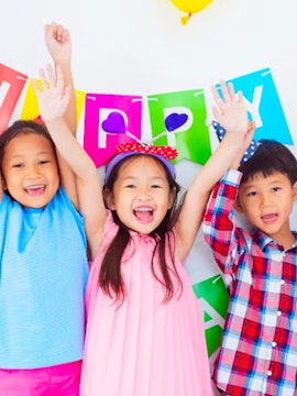 Children celebrating at KidZania with colorful balloons and a birthday banner.