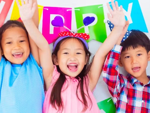 Children celebrating at KidZania with colorful balloons and a birthday banner.