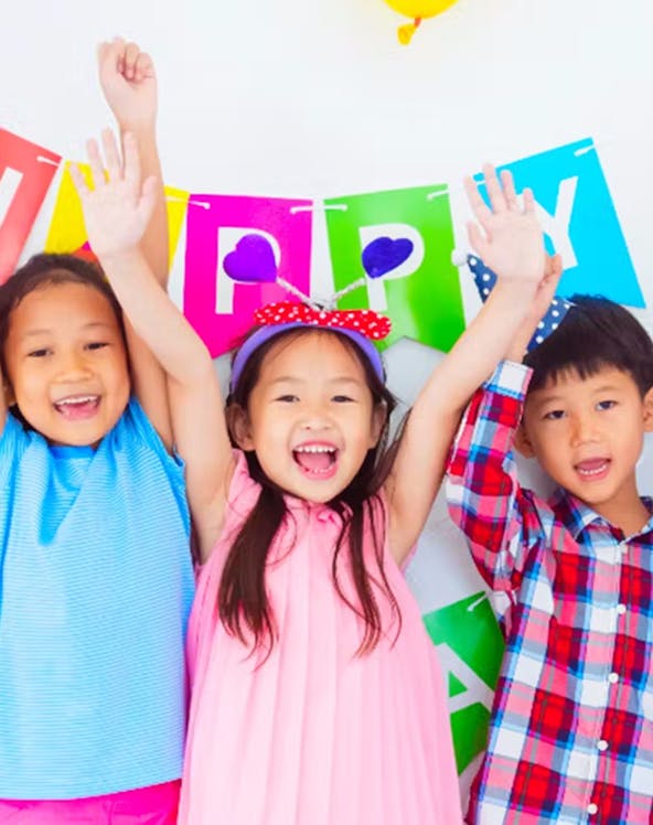 Children celebrating at KidZania with colorful balloons and a birthday banner.