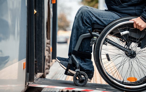 Wheelchair user boarding bus via accessible ramp.