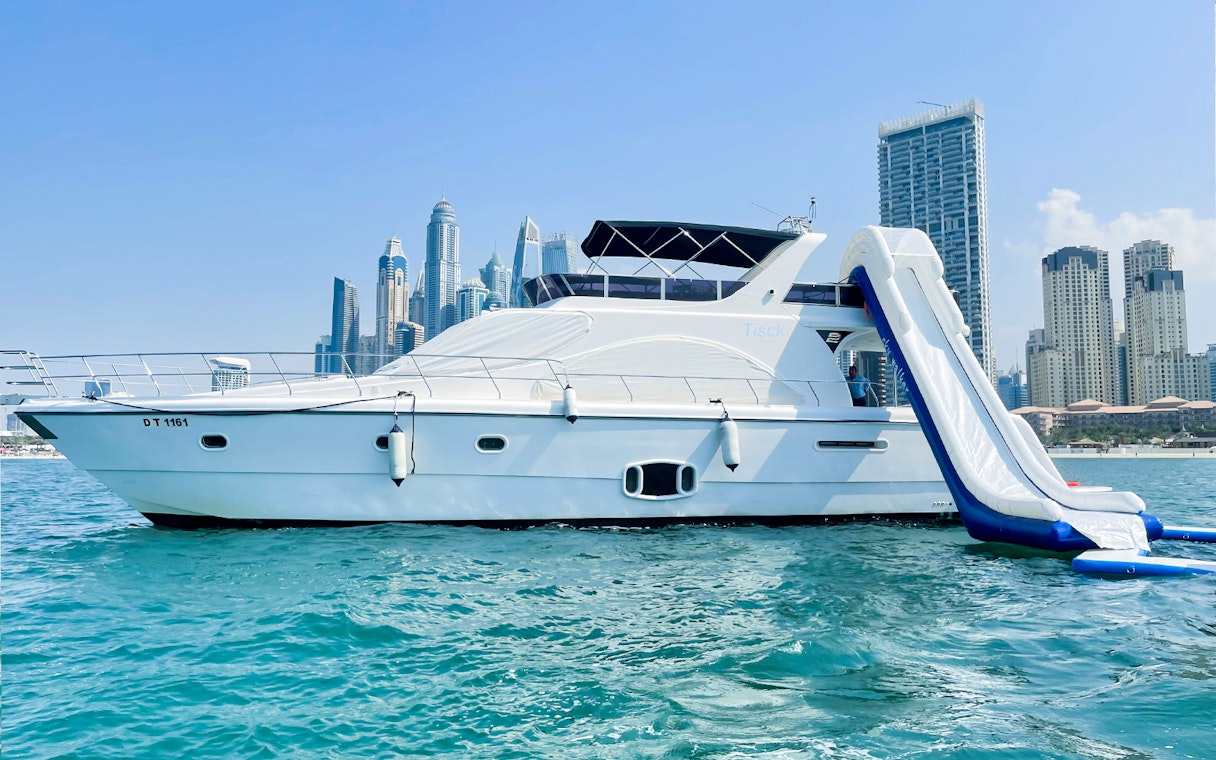 Yacht with slide in Dubai Marina, skyscrapers in background.