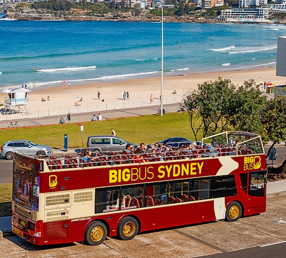 Open-top Big Bus Sydney tour near Bondi Beach with ocean view.