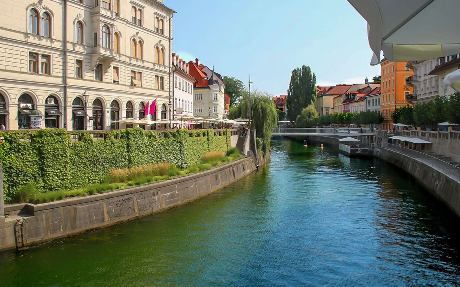 Ljubljanica River flowing through historic city center of Ljubljana with riverside cafes.