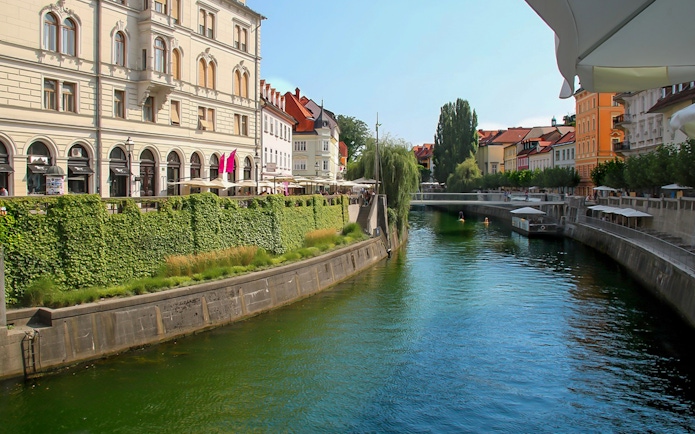 Ljubljanica River flowing through historic city center of Ljubljana with riverside cafes.