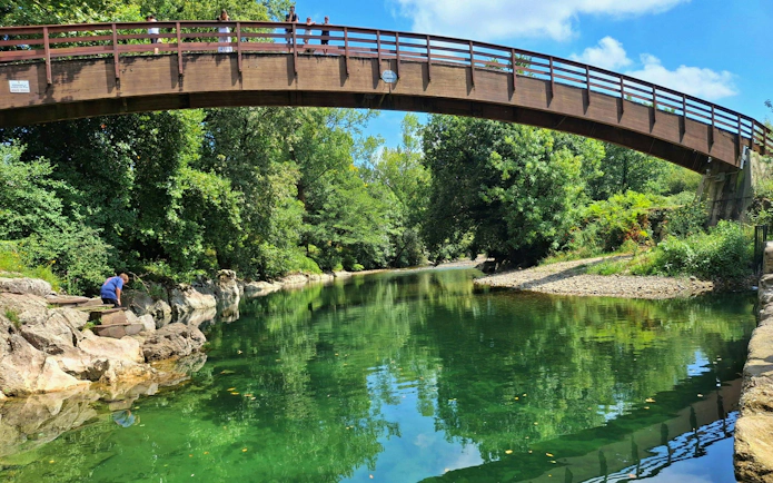 Bridge over a river surrounded by lush greenery on the way to Monte Castillo Caves.