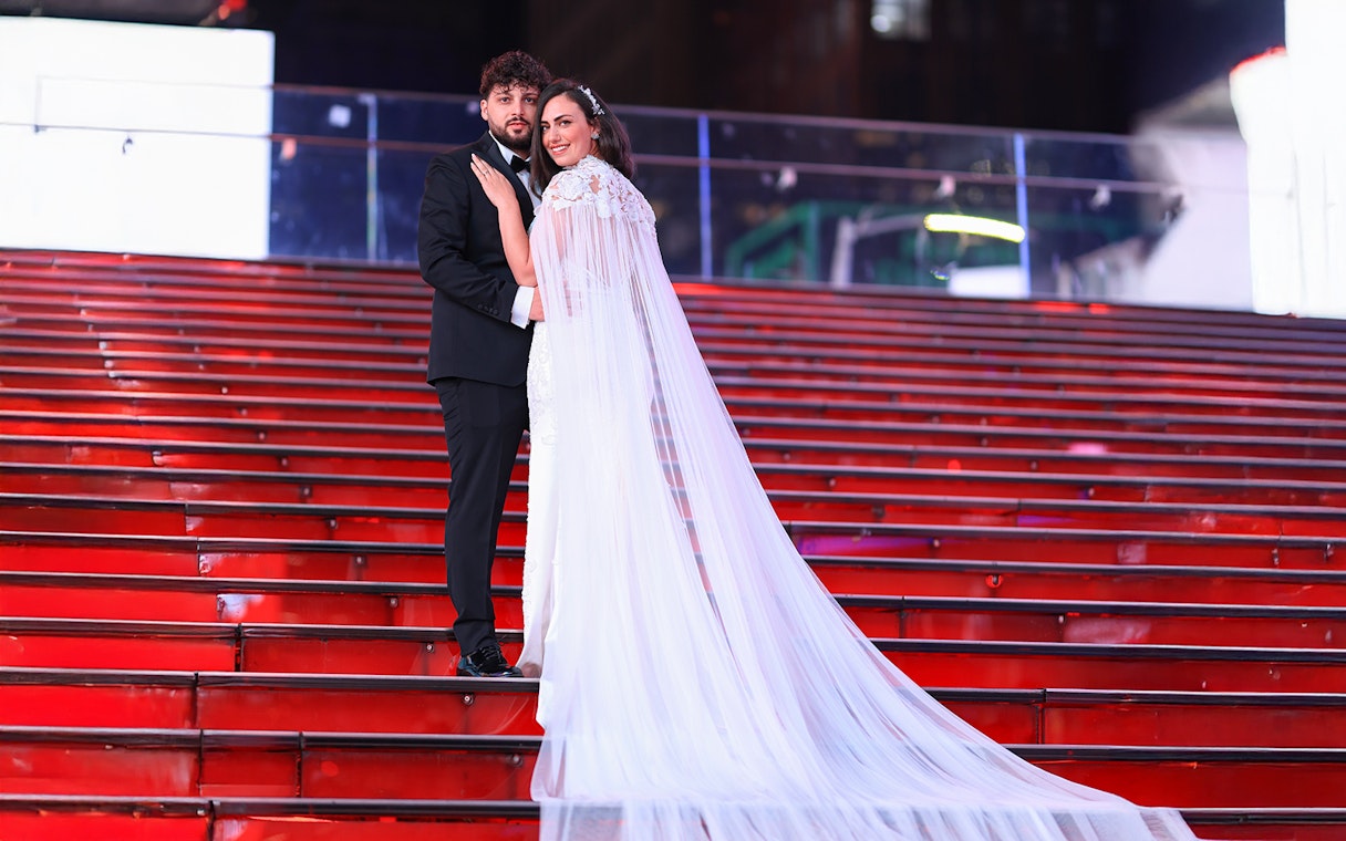 Couple posing on red stairs at Times Square, NYC during a photoshoot.