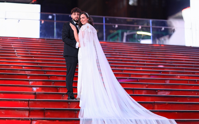 Couple posing on red stairs at Times Square, NYC during a photoshoot.