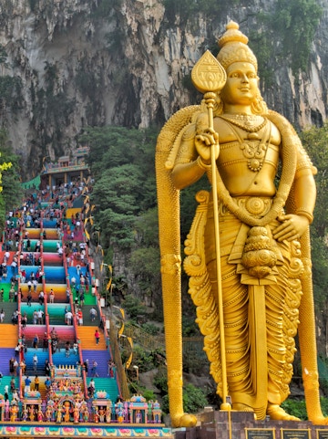 Golden statue of Lord Murugan and colorful steps at Batu Caves, Malaysia.