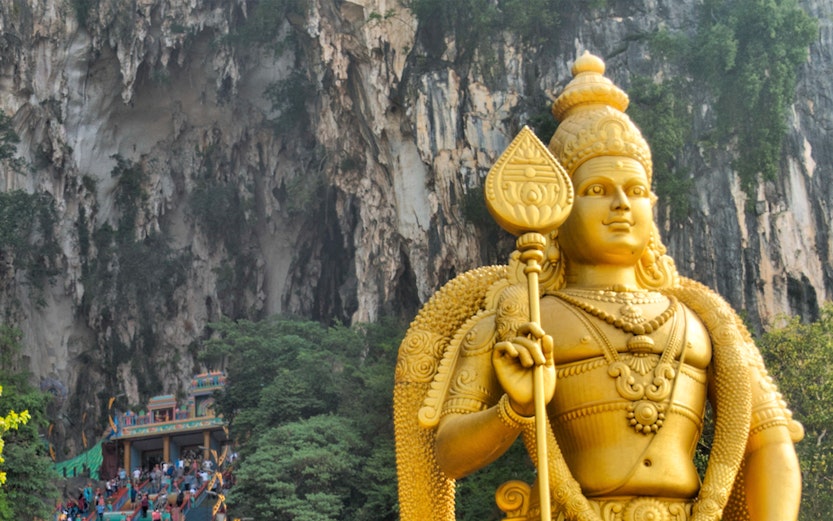 Golden statue of Lord Murugan and colorful steps at Batu Caves, Malaysia.