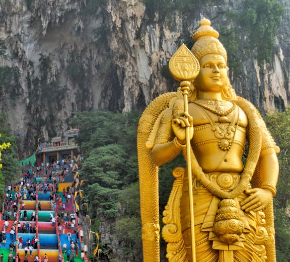 Golden statue of Lord Murugan and colorful steps at Batu Caves, Malaysia.