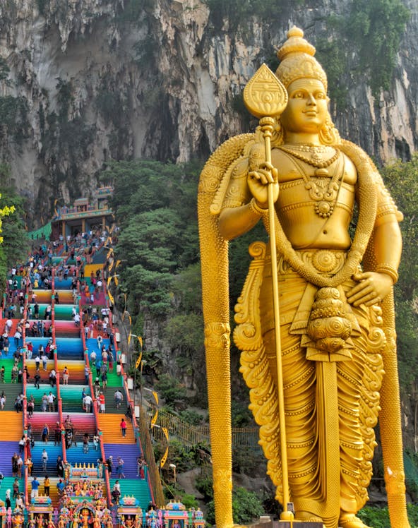 Golden statue of Lord Murugan and colorful steps at Batu Caves, Malaysia.