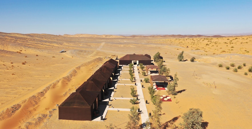 Luxury camp in Merzouga's Sahara Desert with tents and pathways.