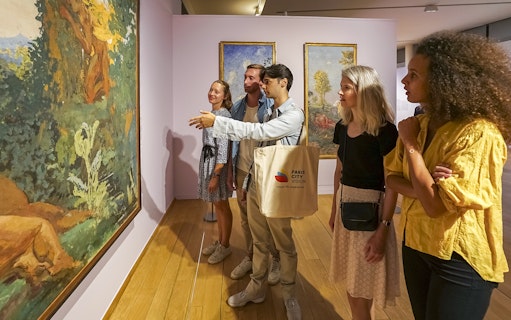 Visitors admiring paintings during a guided tour of Giverny Monet's Gardens from Paris.
