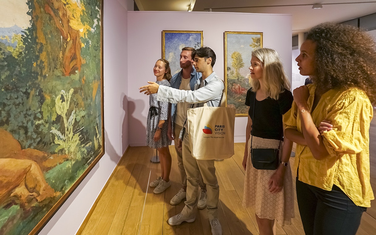 Visitors admiring paintings during a guided tour of Giverny Monet's Gardens from Paris.