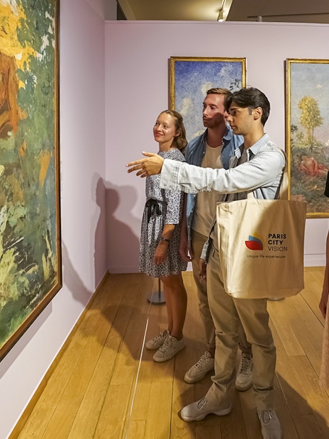 Visitors admiring paintings during a guided tour of Giverny Monet's Gardens from Paris.