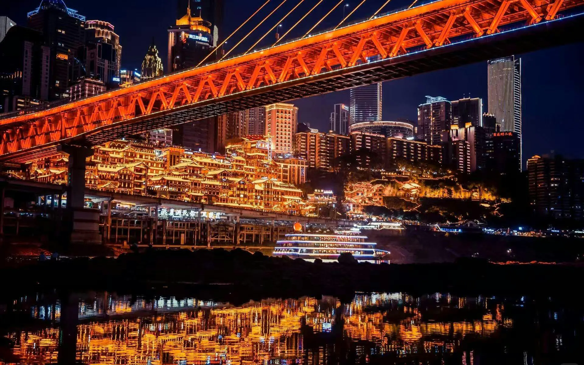 Chongqing Hongyadong lit up at night with city skyline and bridge reflections.