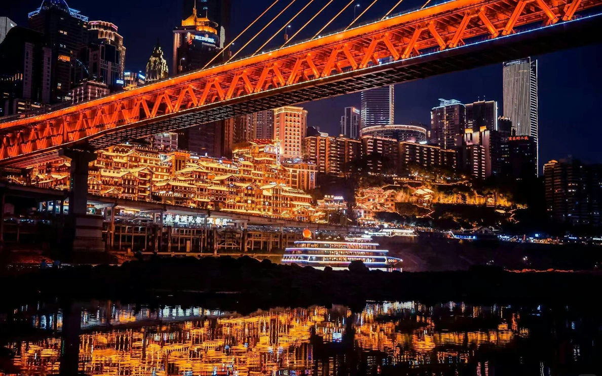 Chongqing Hongyadong lit up at night with city skyline and bridge reflections.