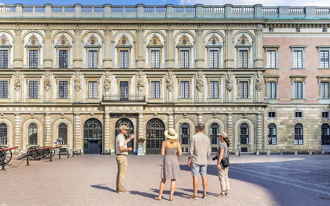 Tour group in front of historic royal palace facade in Stockholm, Sweden.