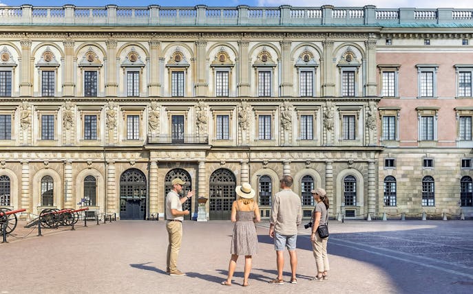Tour group in front of historic royal palace facade in Stockholm, Sweden.