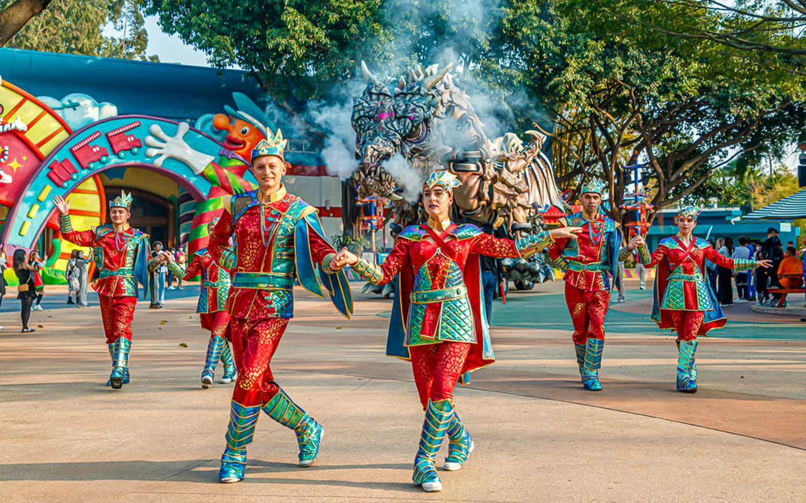 Performers in colorful costumes at Chimelong Paradise with dragon float in background.