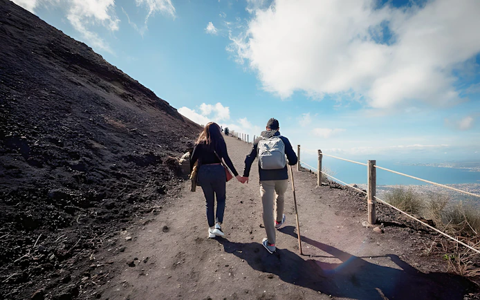 Hikers on a guided tour ascending a trail at Vesuvius National Park near Naples, Italy.
