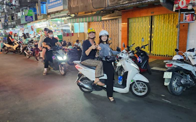 Motorbike riders on Saigon street food tour, Ho Chi Minh City, exploring local districts.