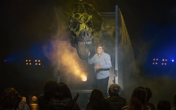 Magician on stage with dinosaur illusion during Vegas show performance.
