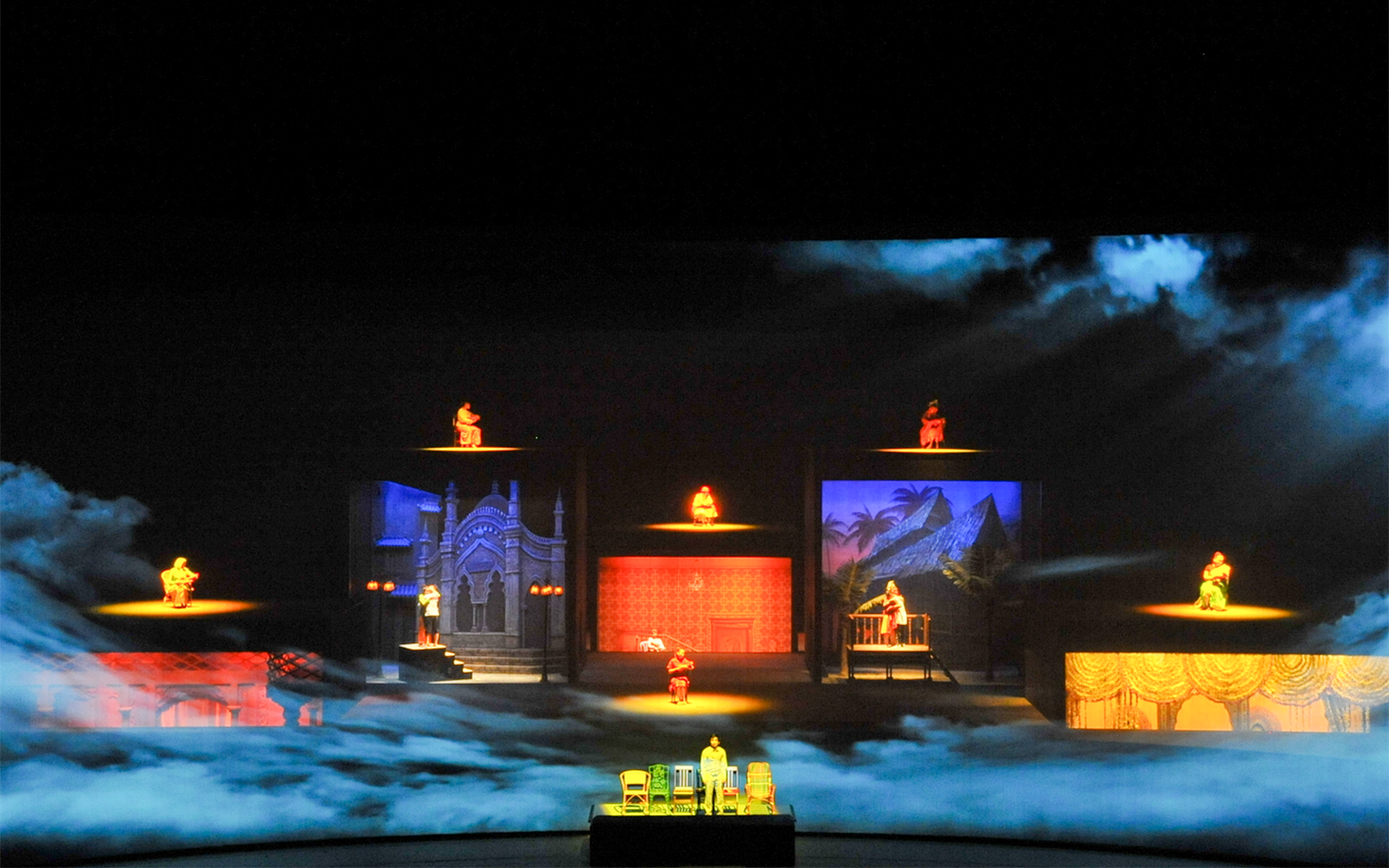 Multi-level stage with performers in colorful attire, showcasing diverse cultural scenes.